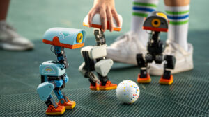 Drei echte Microduck-Roboter von Pollen Robotics mit einem Ball